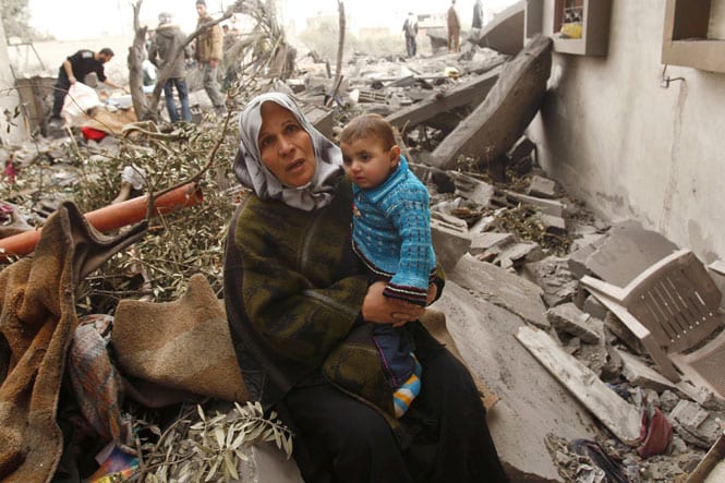 A Palestinian woman sits on the rubble of her destroyed house after an Israeli air strike in Rafah in the southern Gaza Strip on 30 December, 2008