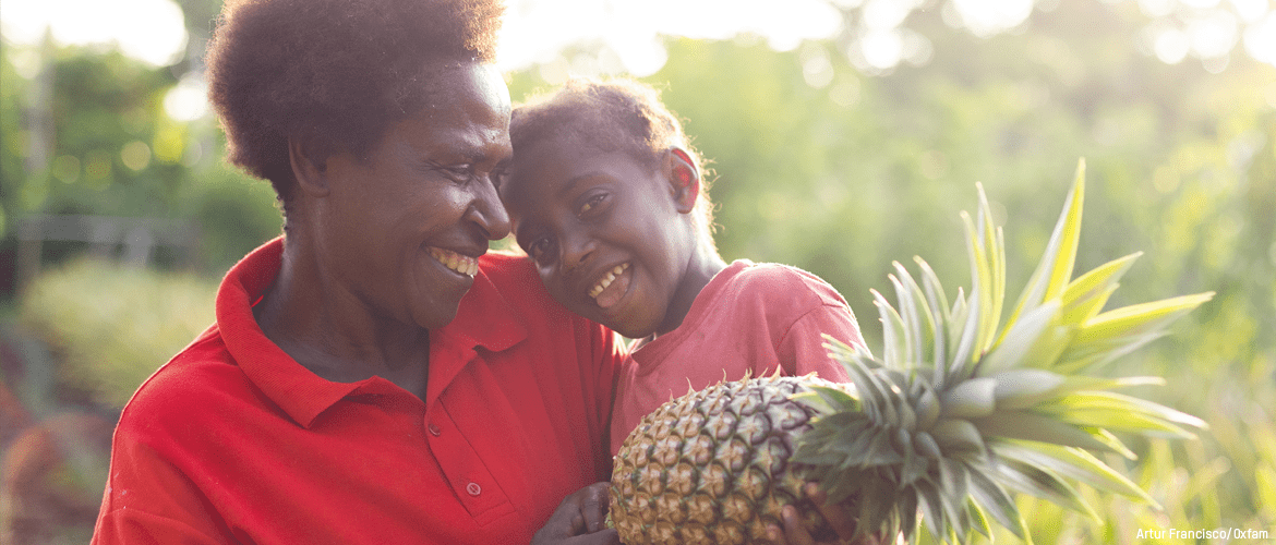 Yvette and her daughter Grace in the fruit and vegetable patches Yvette and her husband maintain with support from Oxfam Partner Farm Support Association, (FSA).