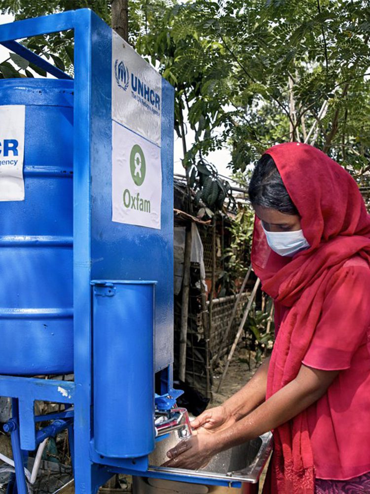 A woman washes her hand from a water tank.