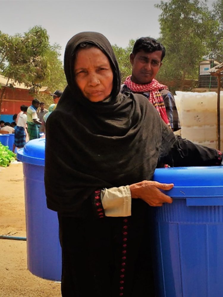 A woman carries a blue bucket.