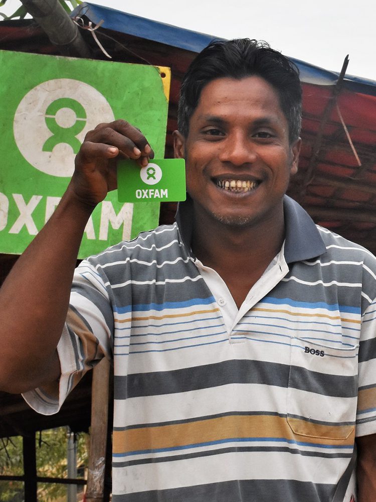 A man holds an Oxfam branded card.