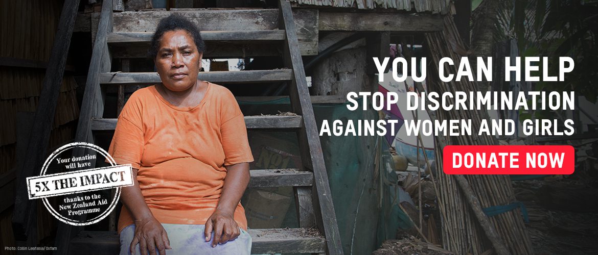 A woman wearing an orange shirt sits on the wooden steps of her home.