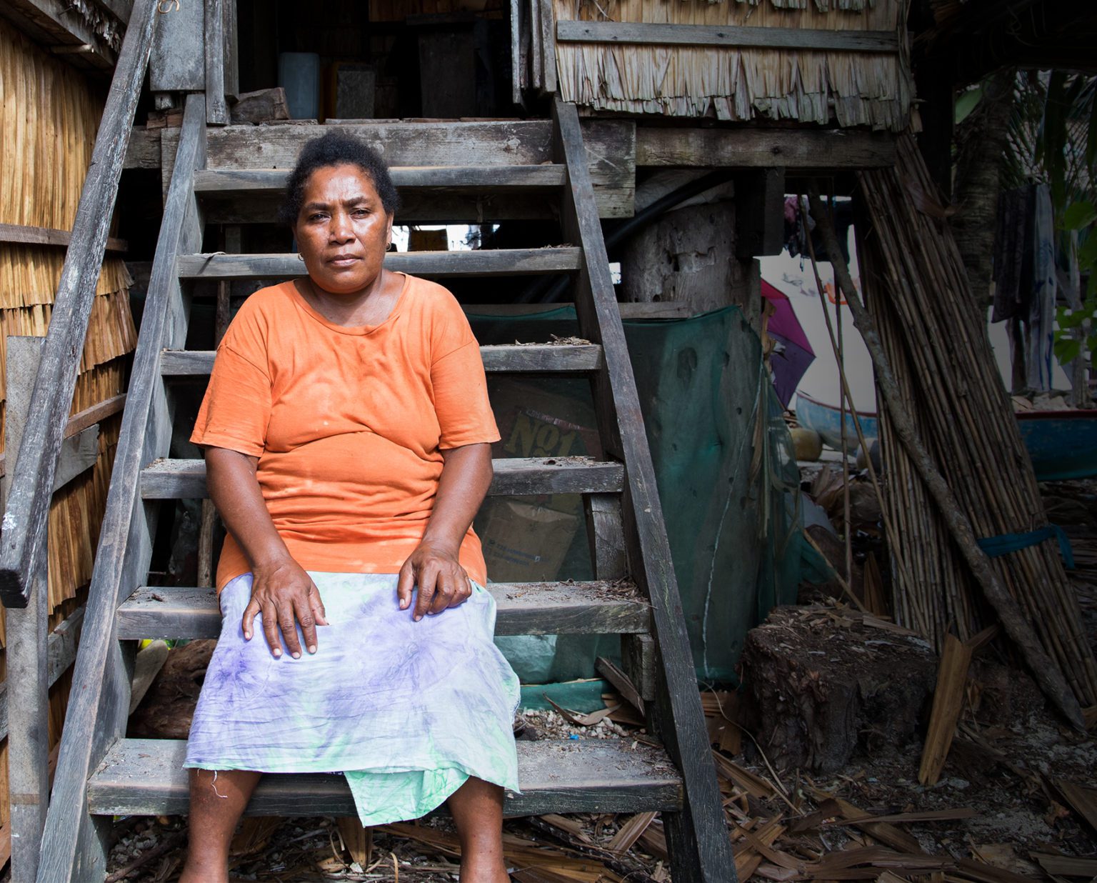 Image of woman wearing an orange shirt sitting on wooden steps.