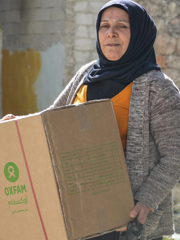 A woman holds a box containing blankets and other winter supplies.