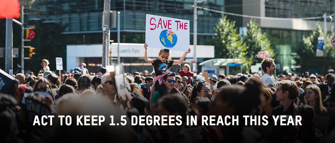 Image of a crowd protesting with test \Áct now to keep 1.5 degrees in reach