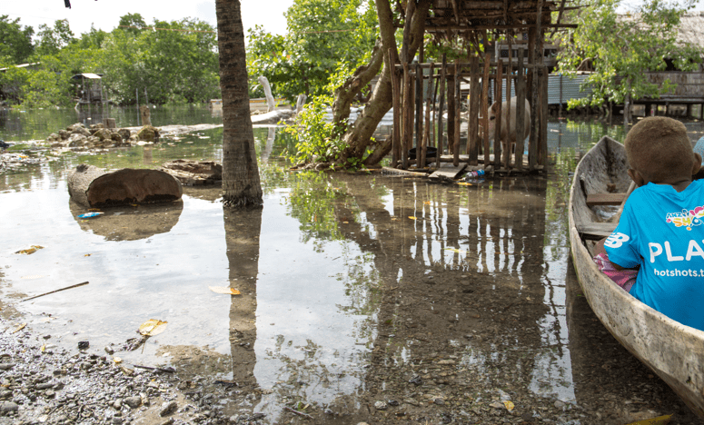 Image of a young boy in a boat, in a flooded area