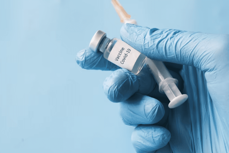 Image of a blue gloved hand holding a vaccine