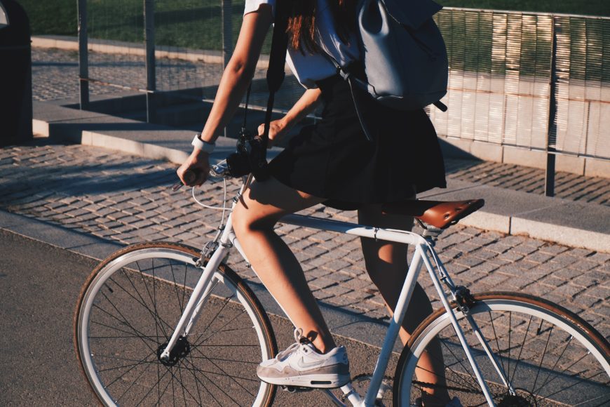 A girl sits on a bike near pavement.