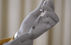 Person with white gloves holding a vaccination
