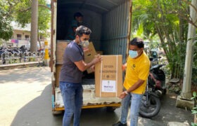 Two men carry a box out of the back of a truck