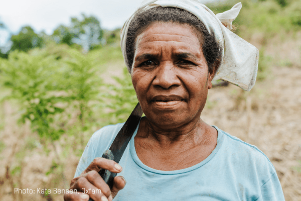 A woman looks towards the camera while holding a tool