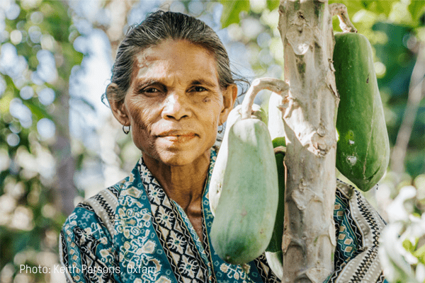 A lady stares towards the camera near a plant