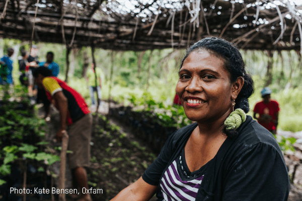 A woman smiles as she sits beside a garden