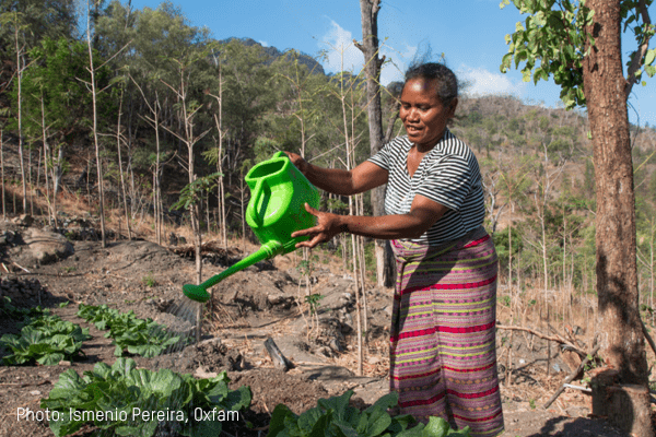 A woman golds a green watering can.