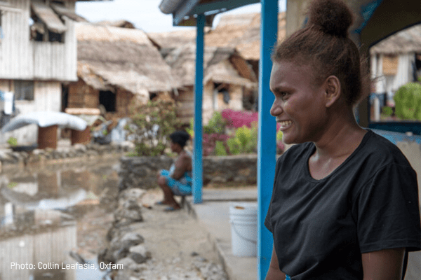 Grace, wearing a black shirt, smiles as she looks out toward her village