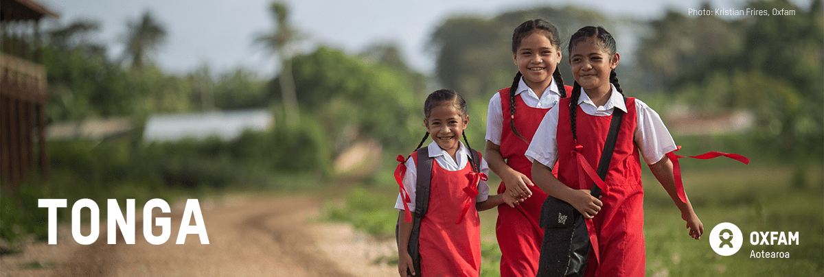 Three girls walk on a clay road in their school uniforms, with text 'Tonga'