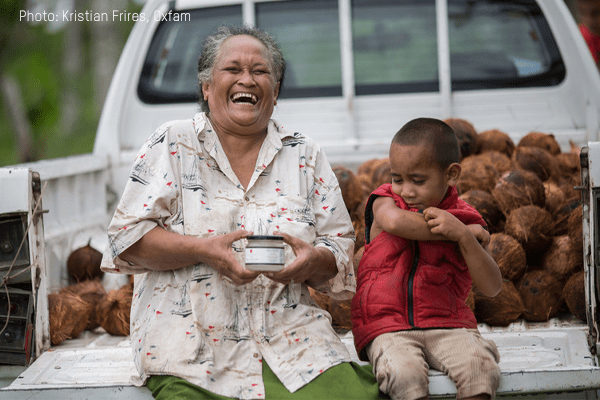 A lady sits, smiling, beside her grandson