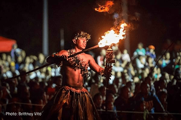 A man holds a fire torch surrounded by a crowd of people