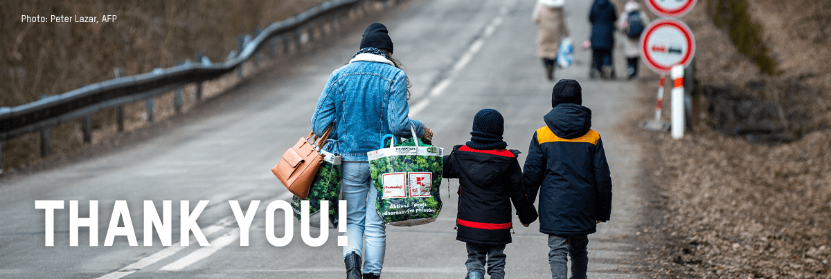 A mother walks down a road with her two children, with text 'thank you'