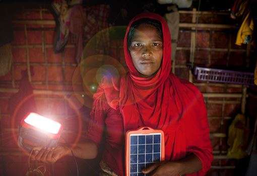 A woman wearing red holds a solar-powered light