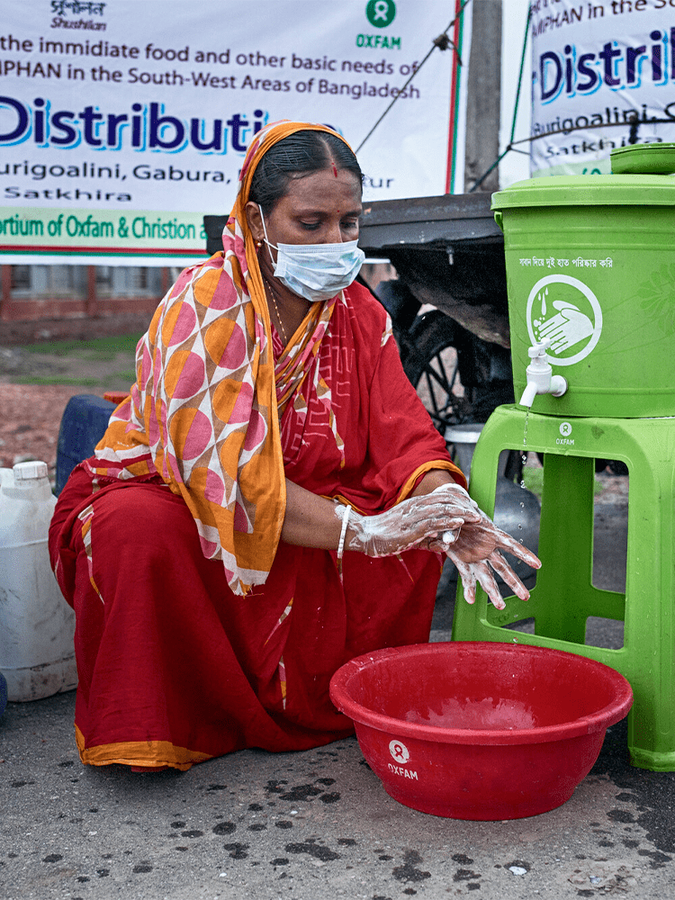 A woman kneels over, washing her hands