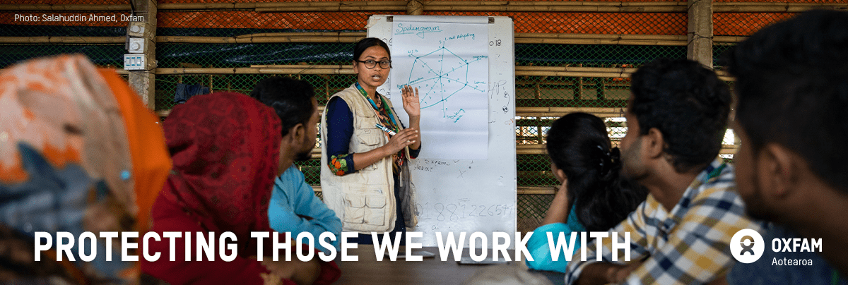 Iffat stands in front of a whiteboard with text 'Protecting those we work with'