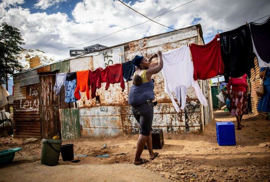 A mother hangs out washing with her baby