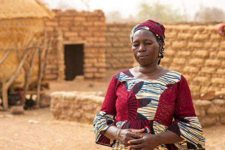 Sanfo stands outside her home