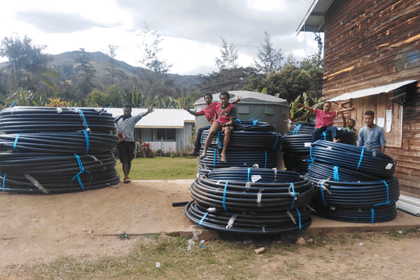 A group of people pose with water system materials in PNG