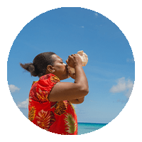 A woman blows a conch shell