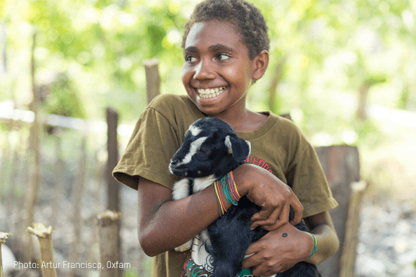 A child smiles holding a goat