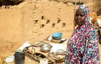 A woman looks toward the camera, beside cooking equipment