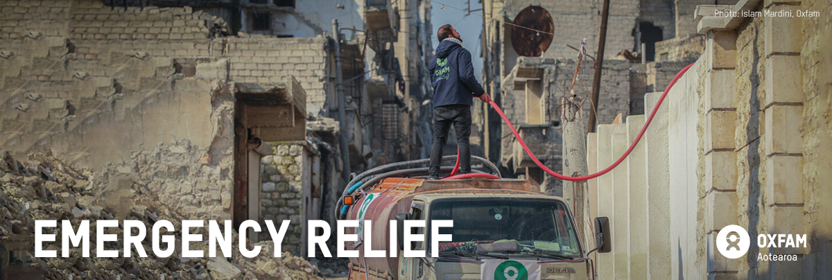 A man standing atop a truck delivering water; text - emergency relief